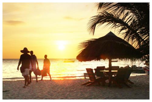 a group of people walking on the beach at sunset at Casa Bambudas in Rincón