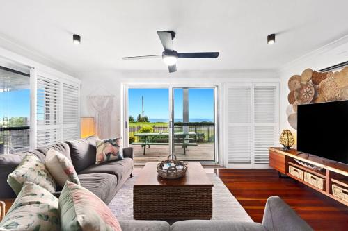 a living room with a couch and a flat screen tv at Quirky Black Shack in Burnett Heads