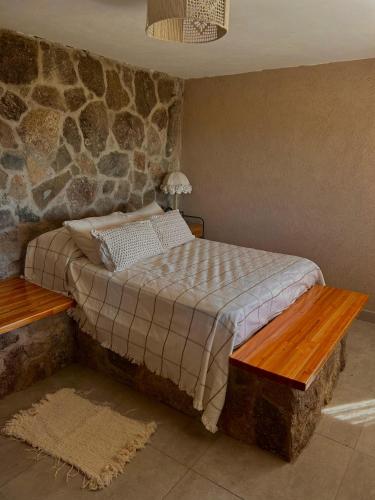 a bedroom with a bed and a stone wall at Cabaña Casa Flor Bru in Villa Yacanto