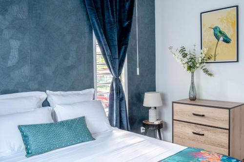 Un dormitorio con una cama con una pared azul. en Madeleine Garden Pool Parking Wifi Netflix, en Cayenne