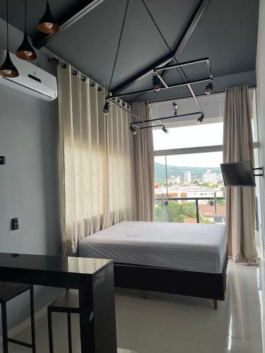 a bedroom with a bed and a desk and a window at Skyloft in Governador Valadares