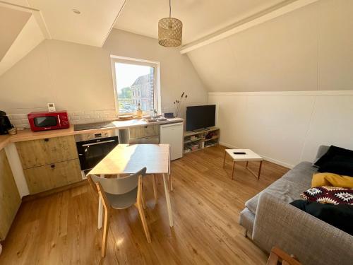 une cuisine et un salon avec une table et un canapé dans l'établissement Gîte à la ferme, T3 Flandres, à Pérenchies
