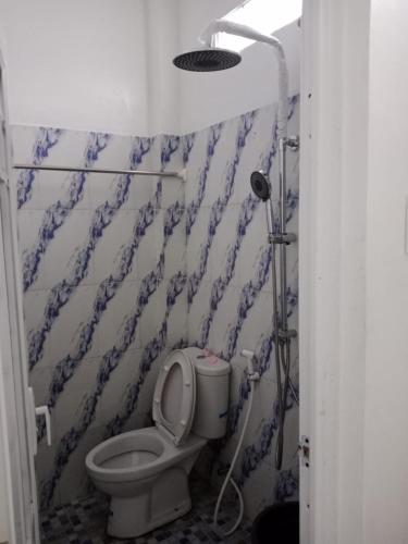 a bathroom with a toilet with a blue and white wall at LA97 Homestay in Berastagi
