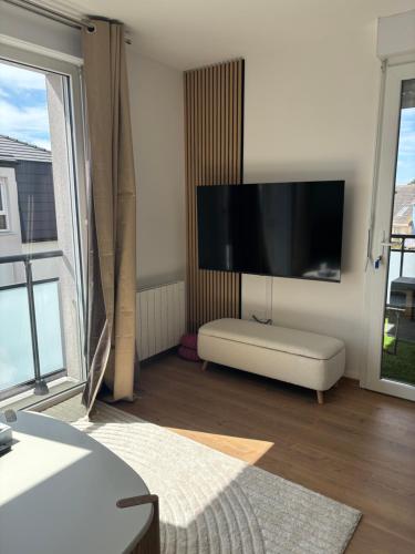 un salon avec une grande télévision à écran plat au mur dans l'établissement L'écrin de Berck - T2 cabine, à Berck-sur-Mer