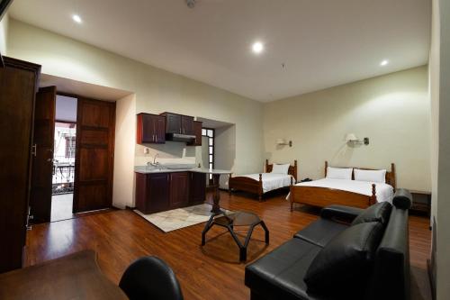 a living room with a bed and a couch and a kitchen at Hotel & Suites El Quijote in Cuenca