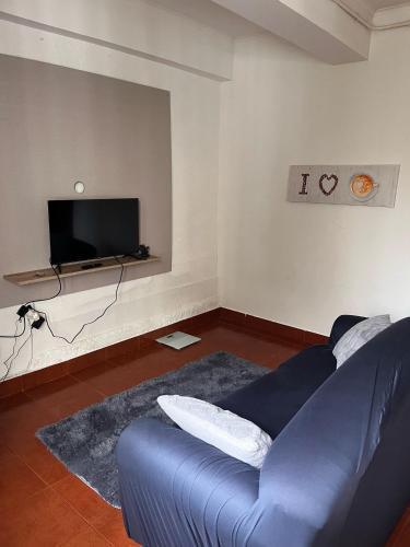 a living room with a blue couch and a tv at JM House in Viseu
