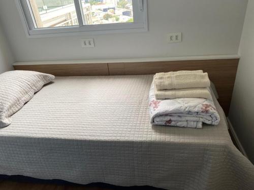 Una cama con sábanas y almohadas blancas y una ventana. en Modern apartment in Pinheiros and Faria Lima, en São Paulo