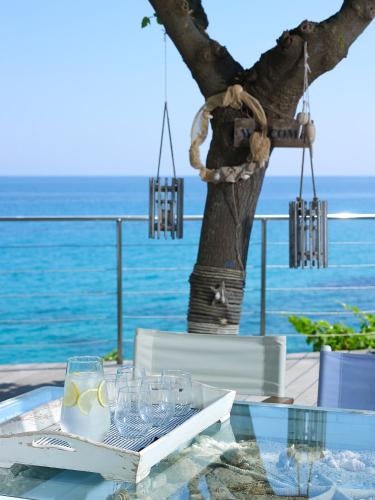 a glass table with a tree and the ocean in the background at Paradisso Beach Villas in Zakynthos Town