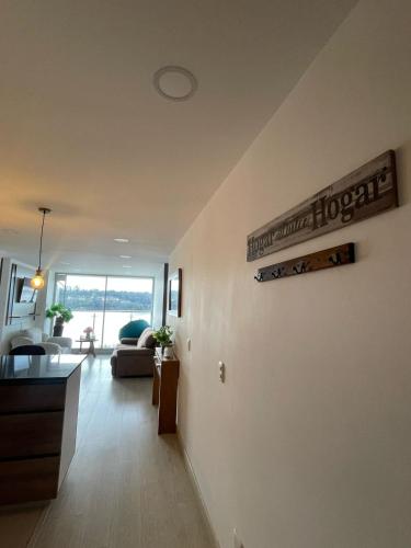 a living room with a couch and a sign on a wall at Apartamento con vista al lago Sochagota in Paipa