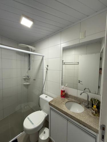 a bathroom with a toilet and a sink and a mirror at Flat - Frente Mar, Roda Gigante e Estrada da Rainha in Balneário Camboriú