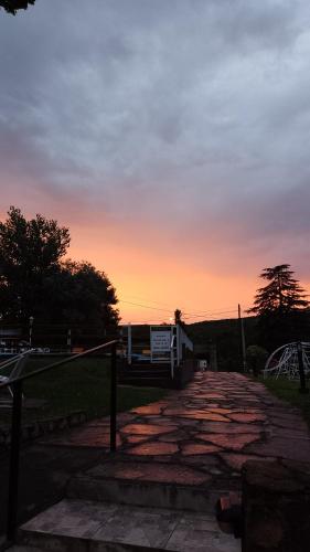 a sunset over a brick road in a park at Ribera Sur Hotel - Los Algarrobos - Tanti in Tanti