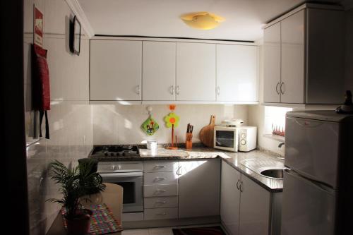 La cuisine est équipée de placards blancs et d'un four avec plaques de cuisson. dans l'établissement Casa do Facho, à Vila Chã