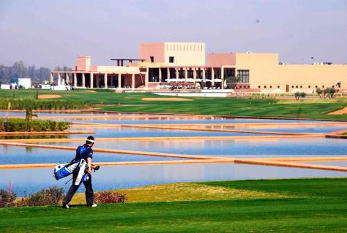 a man walking on a golf course with a group of ponds at Al Maaden Villa Hotel & Spa in Marrakech