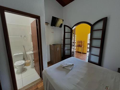 a bedroom with a bed and a bathroom with a toilet at Pousada Pé da Serra in Lindóia