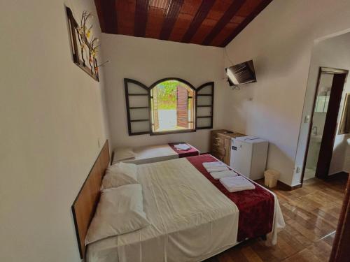 a bedroom with a bed and a window at Pousada Pé da Serra in Lindóia