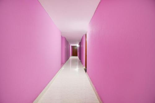 a hallway with purple walls and a white floor at Hotel O The Shivansh Inn in Cuttack