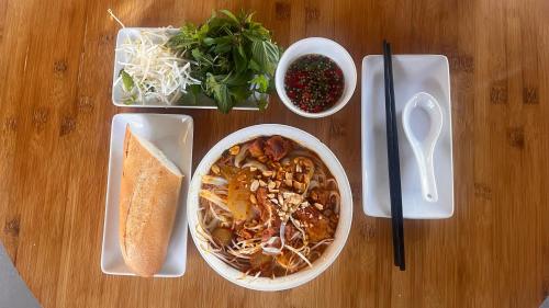 Una mesa de madera con un cuenco de comida y un plato de comida. en Lang Ca Voi The Whales Village Mui Ne, en Mui Ne