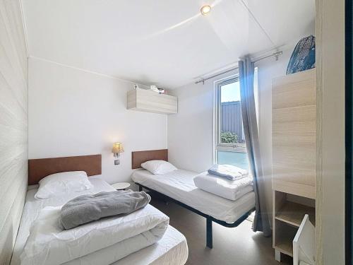 deux lits dans une petite pièce avec une fenêtre dans l'établissement Mobil-Home Confort 6p, 3 Chambres, 2 SDB, Plage à 200m, Piscine Chauffée, Fitness, Wifi Gratuit - FR-1-361A-84, à Jullouville