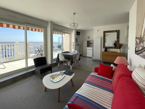 - un salon avec un canapé rouge et une table avec vue dans l'établissement Arcachon - Beau T2 avec grande terrasse vue port - FR-1-420-158, à Arcachon