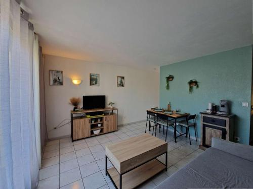 Il comprend un salon doté d'un canapé et d'une table avec une télévision. dans l'établissement Appartement rénové à Marseillan avec terrasse ensoleillée - FR-1-387-213, à Marseillan