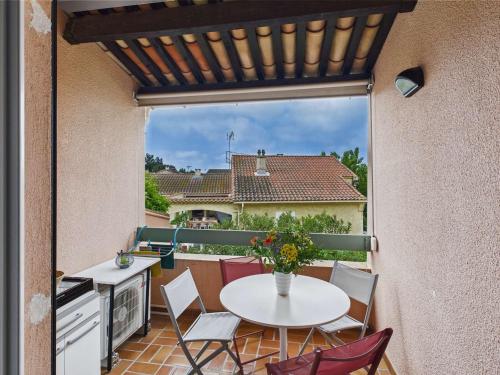un patio avec une table et des chaises blanches sur un balcon dans l'établissement Appartement Climatisé avec Parking, 4 Couchages au Grau d'Agde - FR-1-423-326, au Grau-dʼAgde
