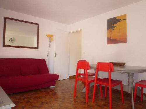 - un salon avec un canapé rouge, une table et des chaises dans l'établissement Appartement 3 Pièces avec Terrasse et Parking Sécurisé - FR-1-750-95, à Canet
