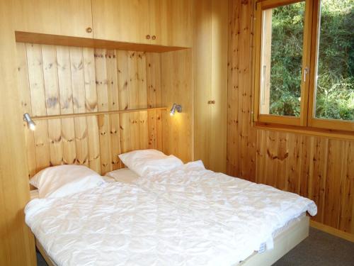 a bed in a wooden room with a window at Alluring apartment in Les Agettes in Agettes