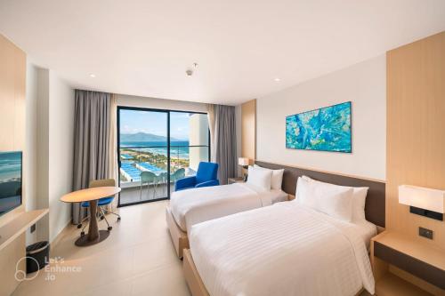 a hotel room with two beds and a window at Arena Cam Ranh Pearl Bay in Cam Ranh