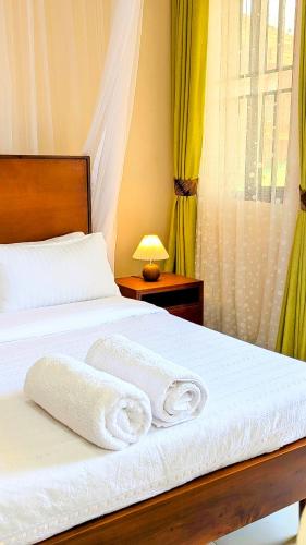 a bedroom with a bed with two towels on it at Ahva III Residence in Jinja