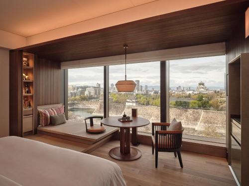 a bedroom with a bed and a table and a large window at Patina Osaka in Osaka