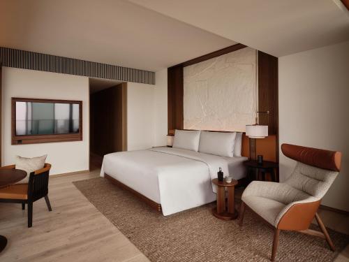 a bedroom with a large white bed and a chair at Patina Osaka in Osaka