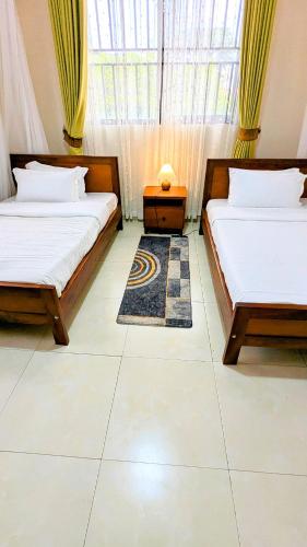 a bedroom with two beds and a rug at Ahva III Residence in Jinja