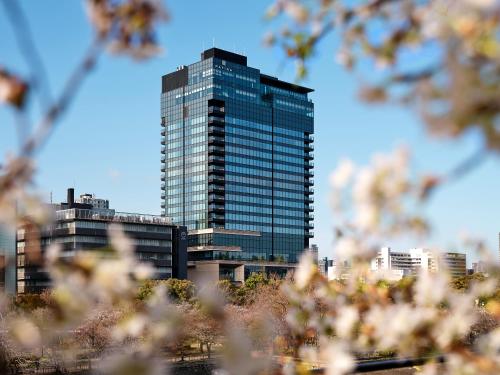 a tall glass building in front of a city at Patina Osaka in Osaka