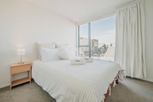 a bedroom with a large bed with a large window at Central 1BR - Bath BBQ & Full Kitchen in Christchurch