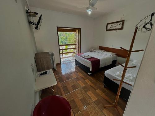 a small room with two beds and a window at Pousada Pé da Serra in Lindóia
