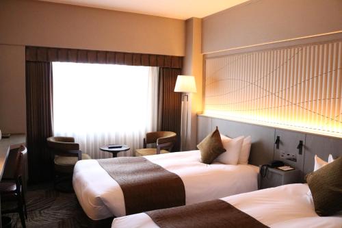 a hotel room with two beds and a window at Hotel New Otani Tottori in Tottori