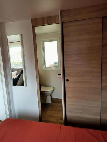 La salle de bains est pourvue d'une porte et de toilettes. dans l'établissement Bungalow confortable près de Condrieu avec piscine partagée, à Condrieu