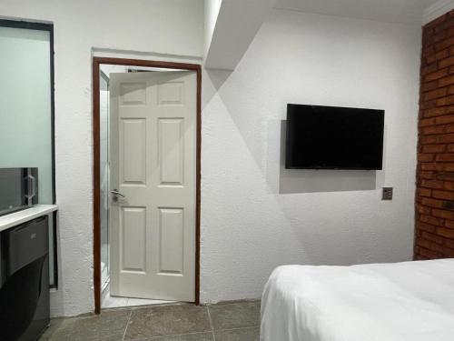 ロードポートにあるStay In Carlazo - Unlimited WiFi Solar backupの白いドアと壁にテレビが備わるベッドルーム1室