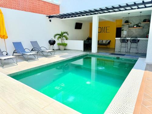 a swimming pool with chairs and a table in a building at CASA VILLA DEL SOL con alberca climatizada in Tonatico