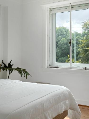 a white bedroom with a white bed and a window at Classic Timeless Palermo Retreat in Buenos Aires