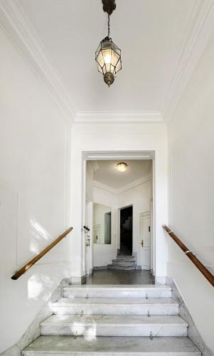 a white hallway with stairs and a chandelier at Classic Timeless Palermo Retreat in Buenos Aires
