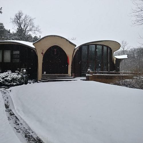 a building covered in snow with a pile of snow at HOUSE Of THE FUTURE IN THE WOODS OF WEST LANSING in Lansing