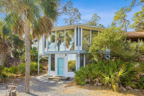 a house with a blue door and a palm tree at Sunset Breeze Marsh View Treehouse Retreat in Fripp Island