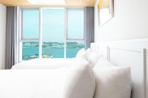 a bedroom with two white beds and a large window at Brown Suites Busan Station in Busan