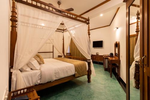 a bedroom with a canopy bed and a desk at La Moon Puducherry in Puducherry