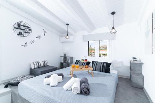 a white bedroom with a bed with towels on it at Kalamaki-Sunset - Scenic Sunset & Sea Views - Steps from Shore! in Kalamaki Heraklion