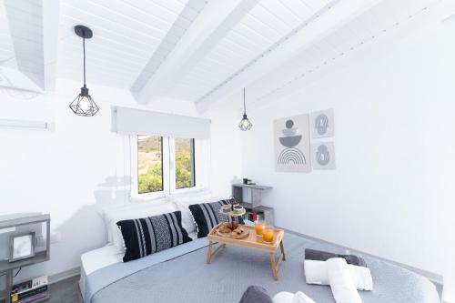 a white room with a bed and a table at Kalamaki-Sunset - Scenic Sunset & Sea Views - Steps from Shore! in Kalamaki Heraklion