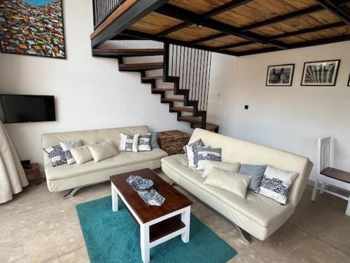 a living room with two couches and a coffee table at Jacaranda Cottage, Rugando in Kigali