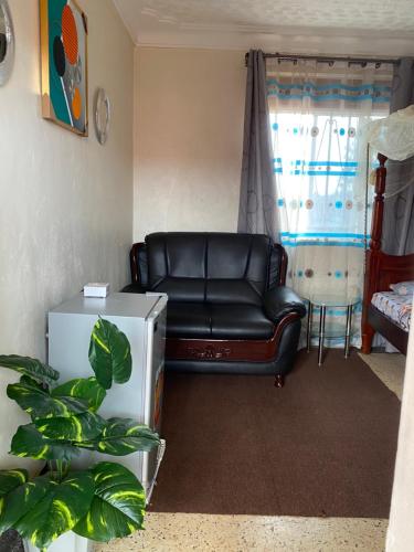a black leather couch in a room with a window at Kabale studio apartments in Kabale