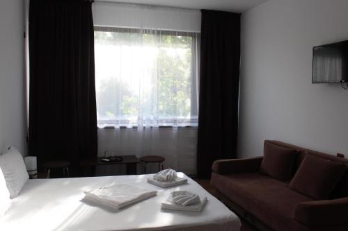 a bedroom with a bed and a couch and a window at Paradox Oituz in Eforie Sud